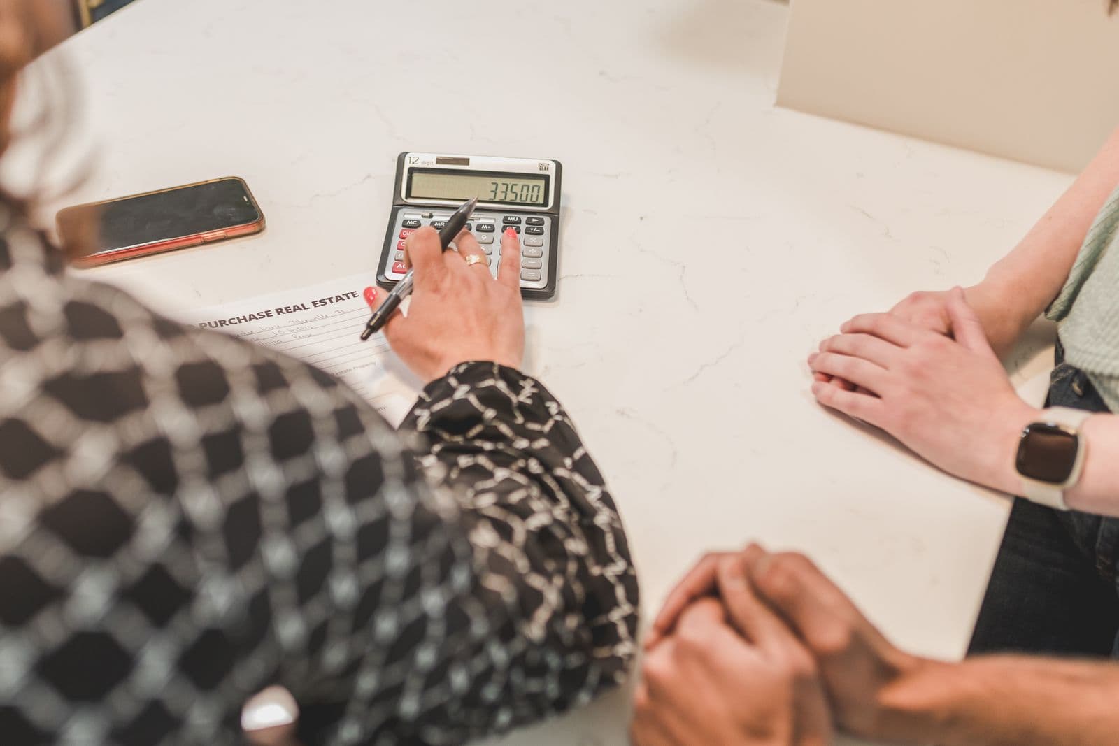 People comparing real estate purchase figures with a calculator and paperwork